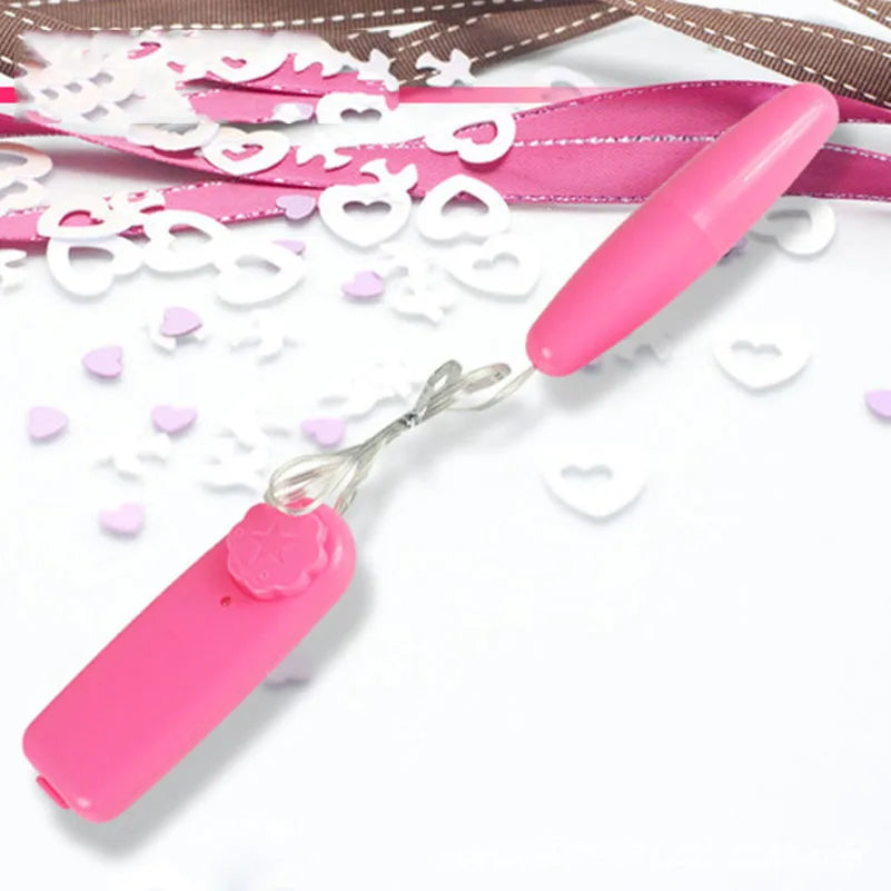 Pink personal massager with wired remote, surrounded by pink and white heart-shaped confetti on white background