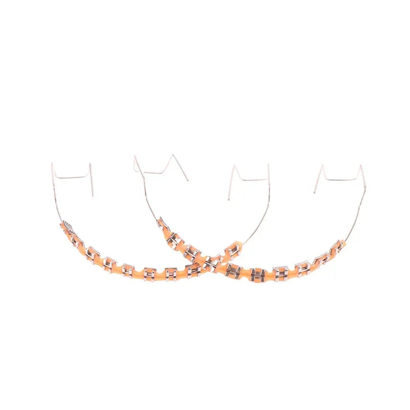 Orthodontic metal braces with orange ligature ties on white background